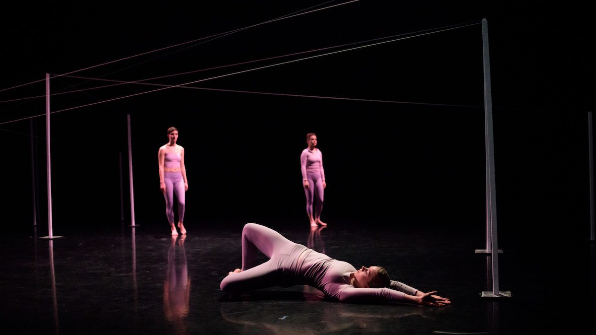 Three people on stage surrounded by a thread.