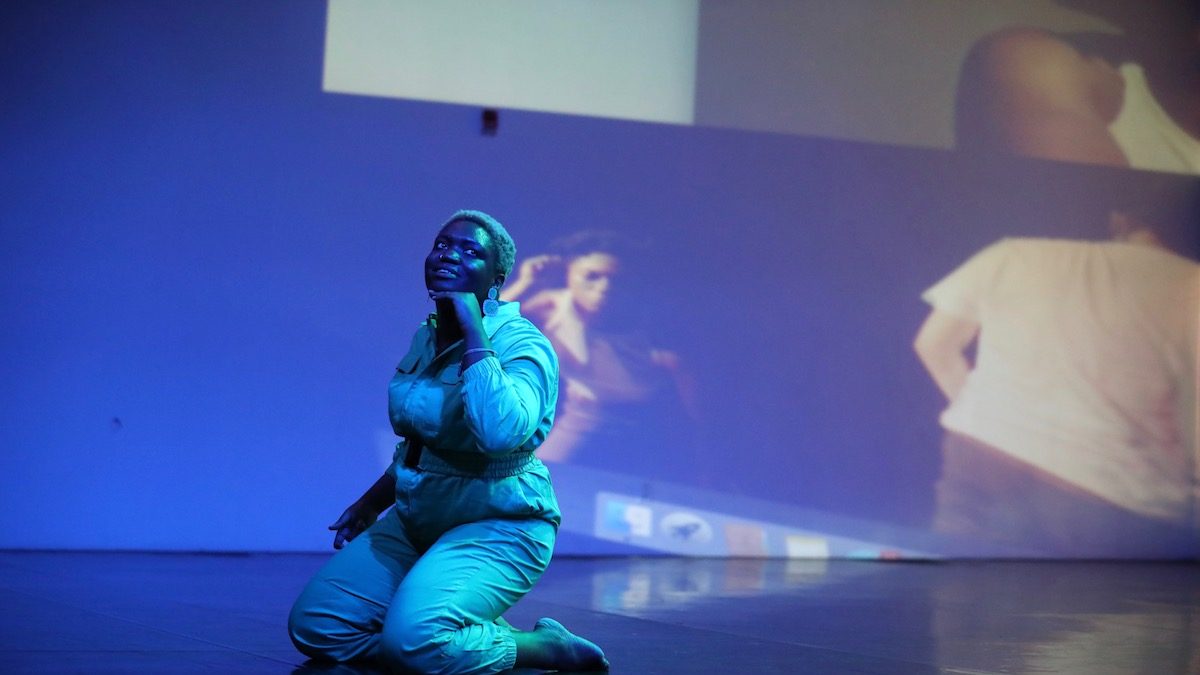 Ogemdi Ude kneeling on a saturated blue lit stage.