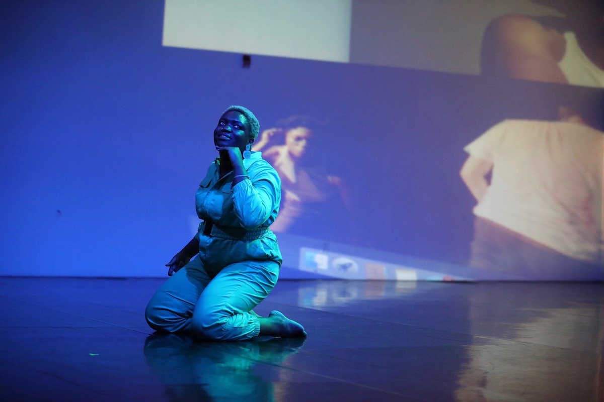 Ogemdi Ude kneeling on a saturated blue lit stage.