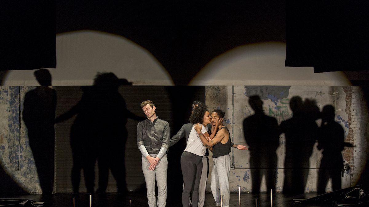 Group of people standing and kissing each other on stage brightly lit.