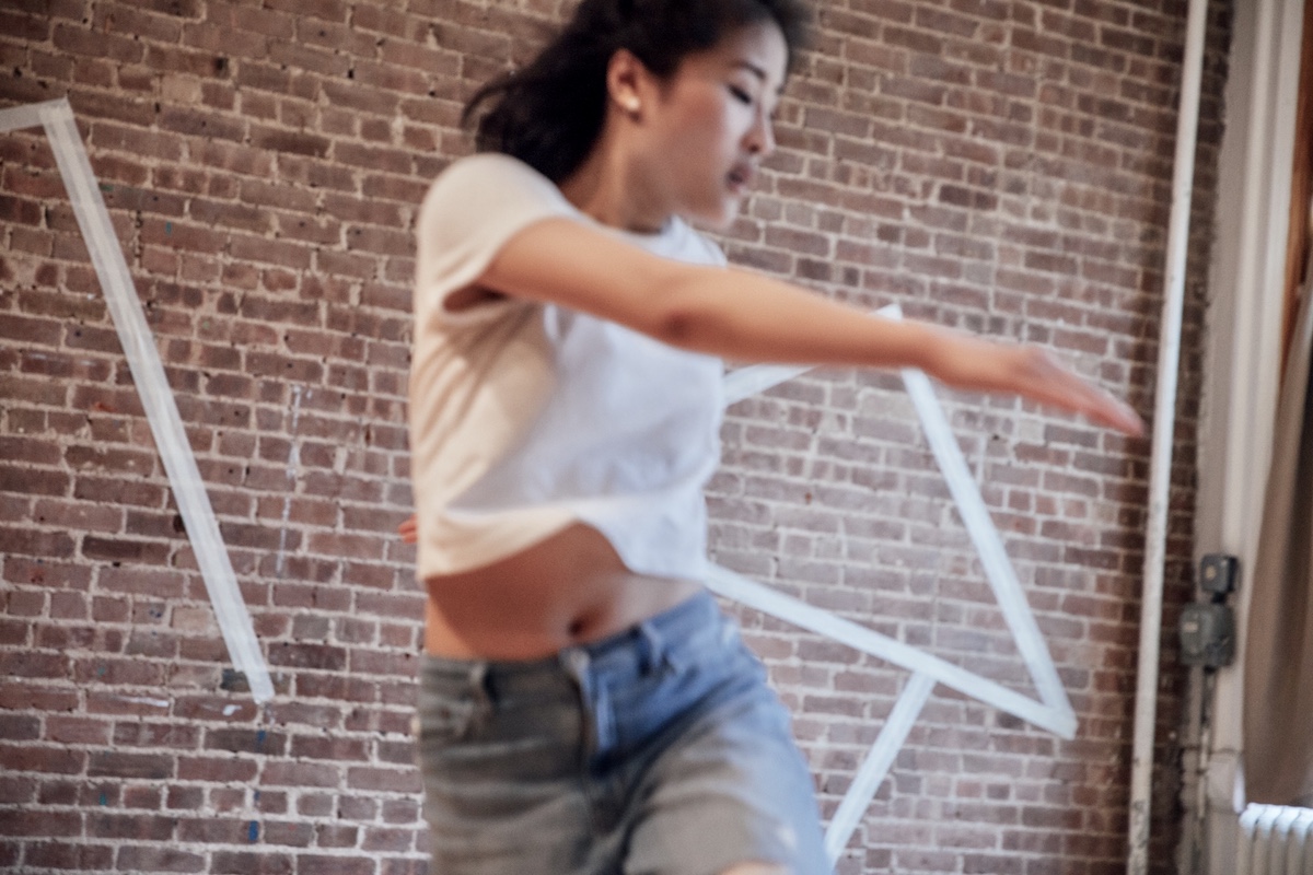 Blurred asian woman in motion in front of a brick wall.