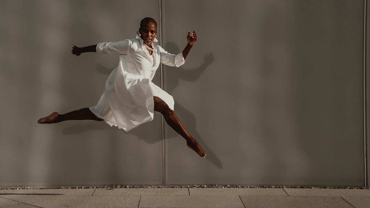 Hope Boykin leaps across the frame in profile, in a billowing white skirt.