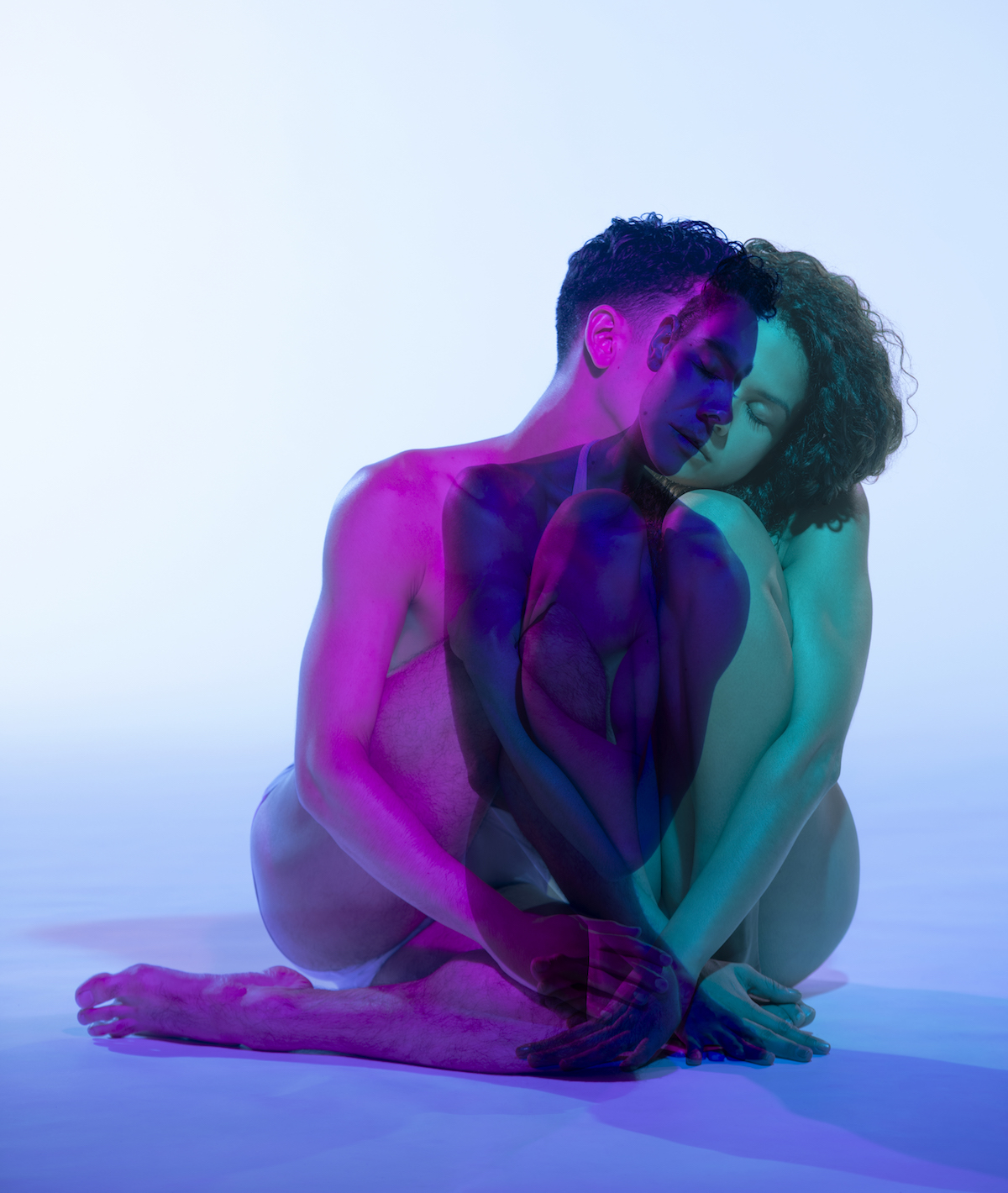 Two people's bodies saturated in purple and green. Their bodies overlap.