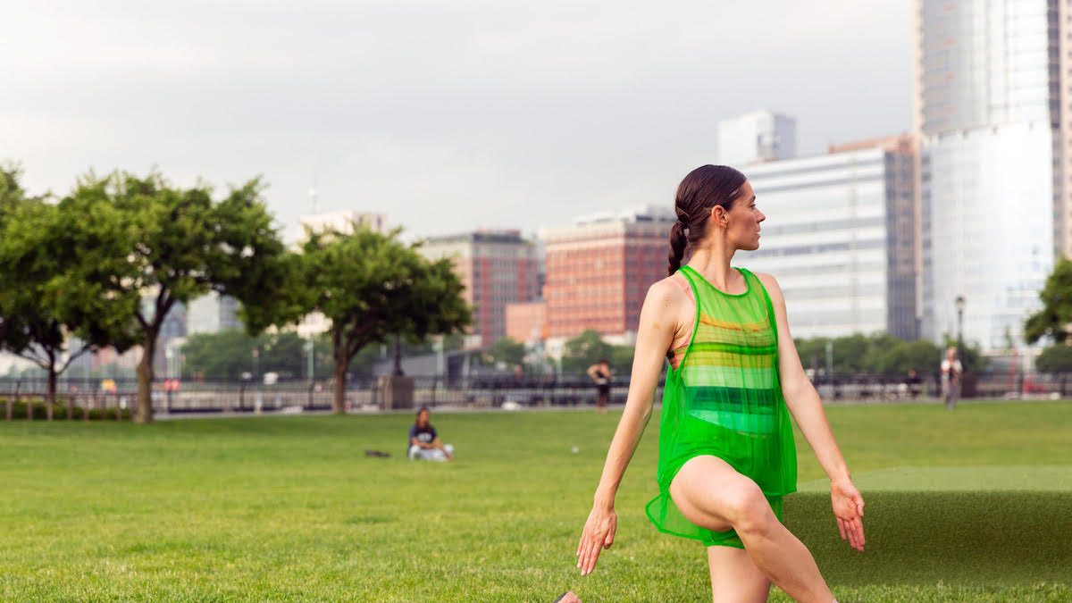 Woman on a lawn in a still sculptural position.