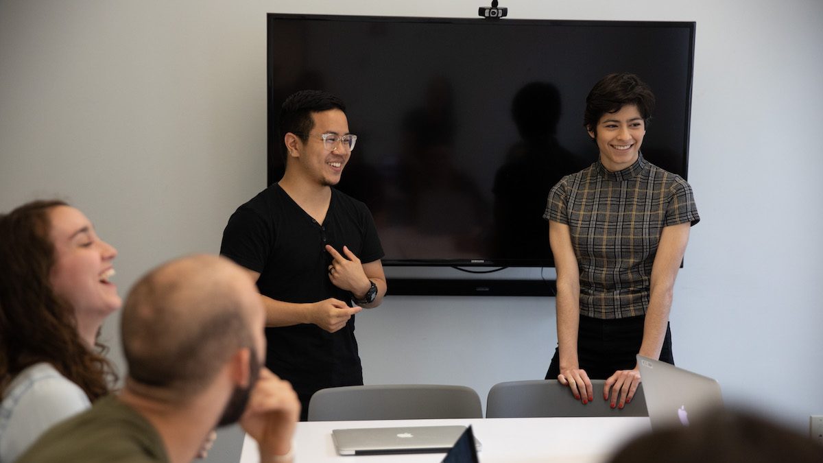 Four people talking and smiling in an office together.