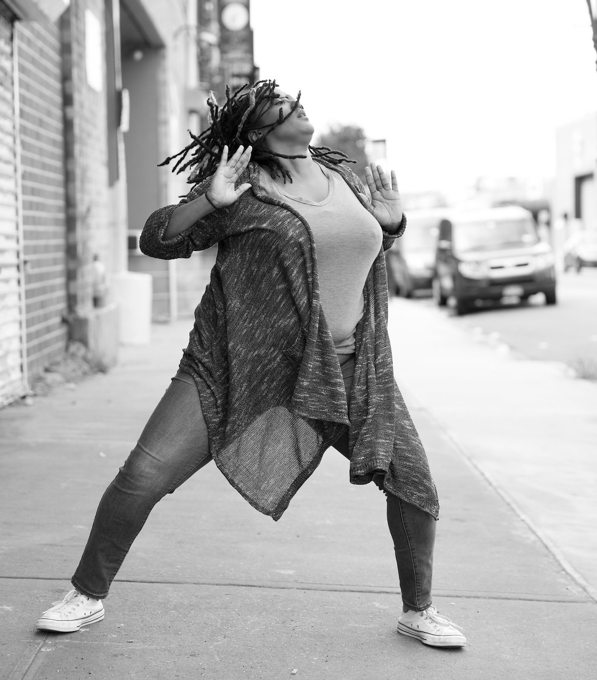 Black and white photo of a black woman dancing on the street.