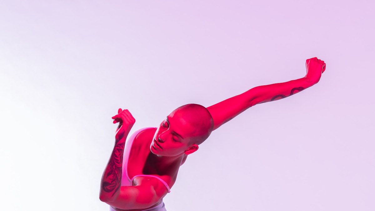 Woman in a saturated pink light as she moves.