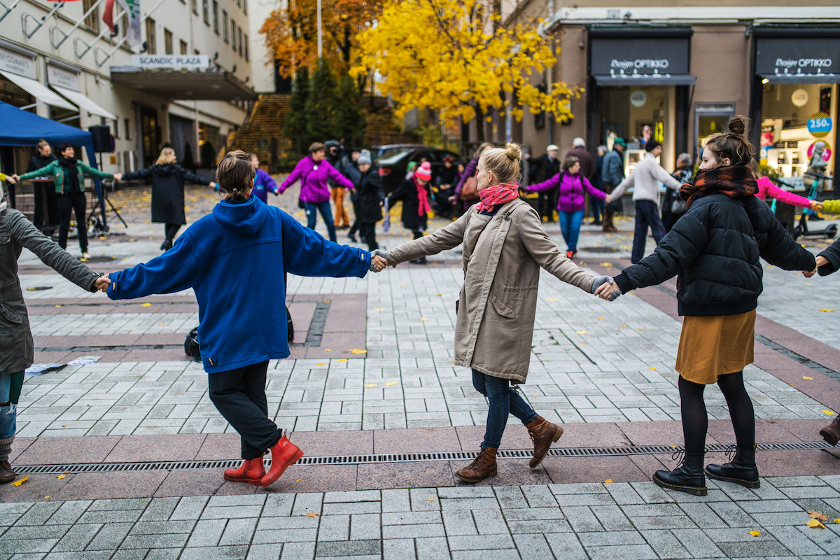 Group of people holding hands in a circle on the street.