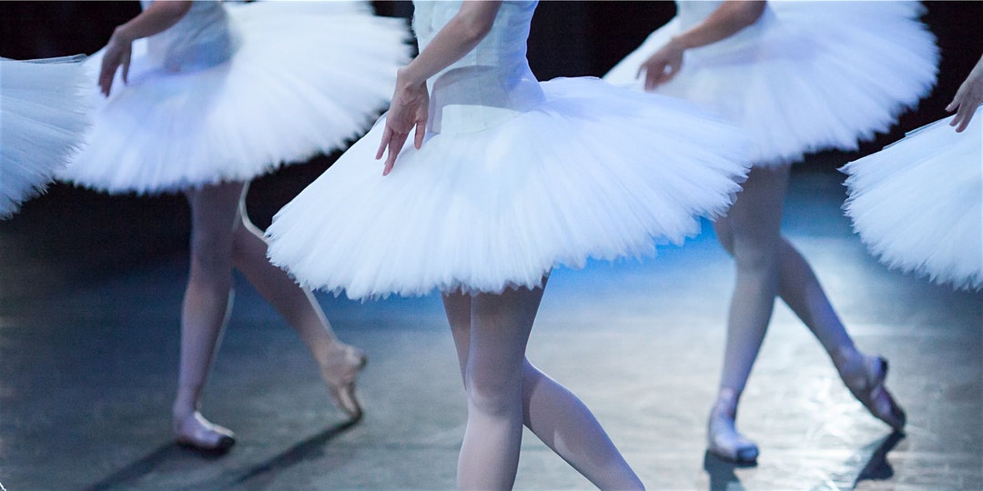 Cropped photo of ballerinas on stage in tutus.
