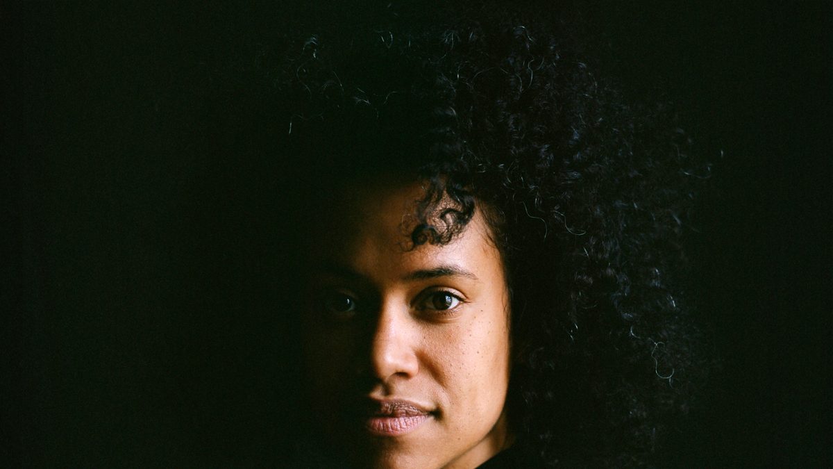 Woman of color's portrait in a deep black background.