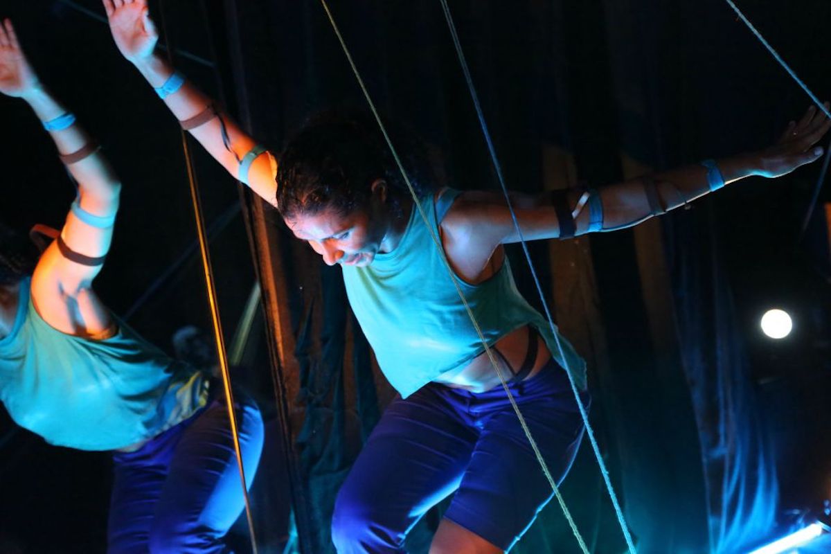Woman leaning forward as she dances in between strings.