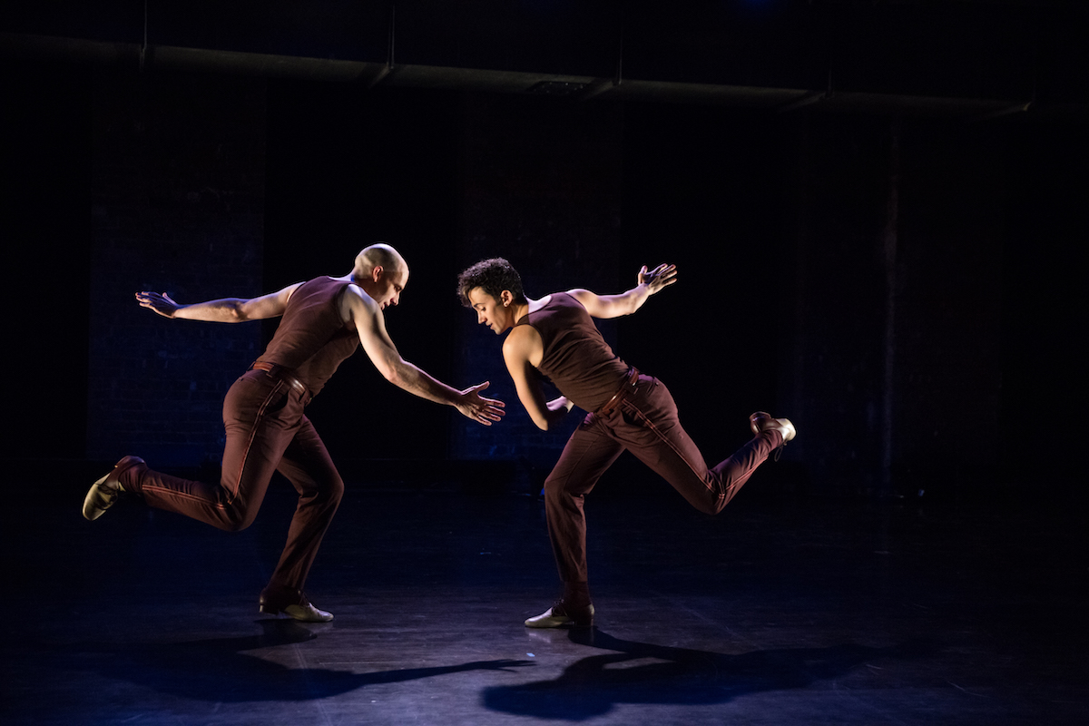 Two people dancing on stage as they lean-in toward eachother.