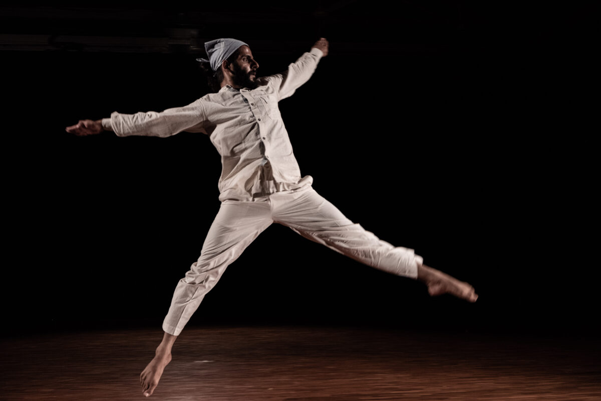Photo of Ainesh Madan in an all white costume jumping.