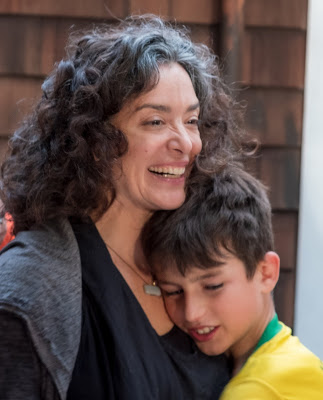 White woman and her son hugging and smiling.