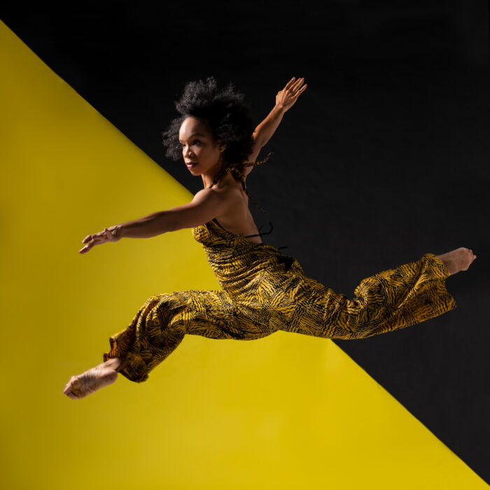 Black woman jumping in the air in a stag dance position.
