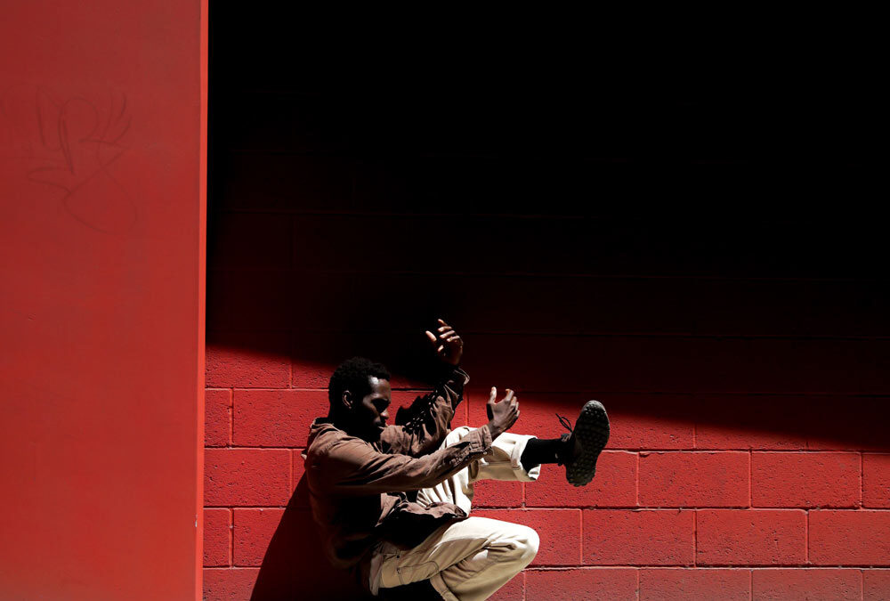 Jarmaine Spivey dancing in front of red wall.