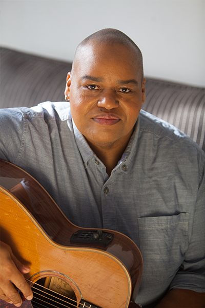 Toshi Reagon holds guitar in sunlight room.